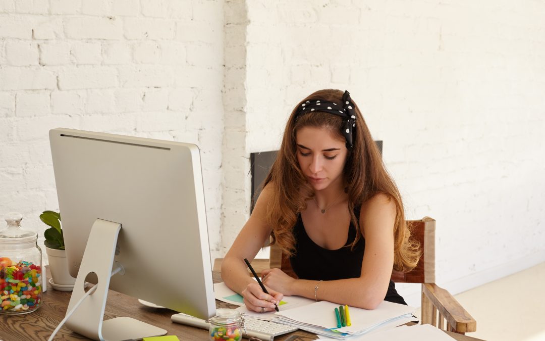 portrait of mindful young female studying foreign languages on internet website making notes on stickers for better memorise new words copy space wall for advertising content or text