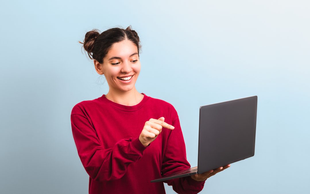 young attractive woman student with funny face holding laptop and pointing into it applaying for university or college enrolment