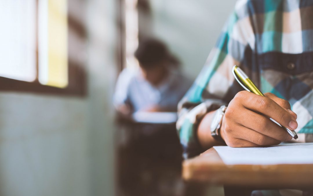 close up students writing and reading exam answer sheets exercises in classroom of school with stress