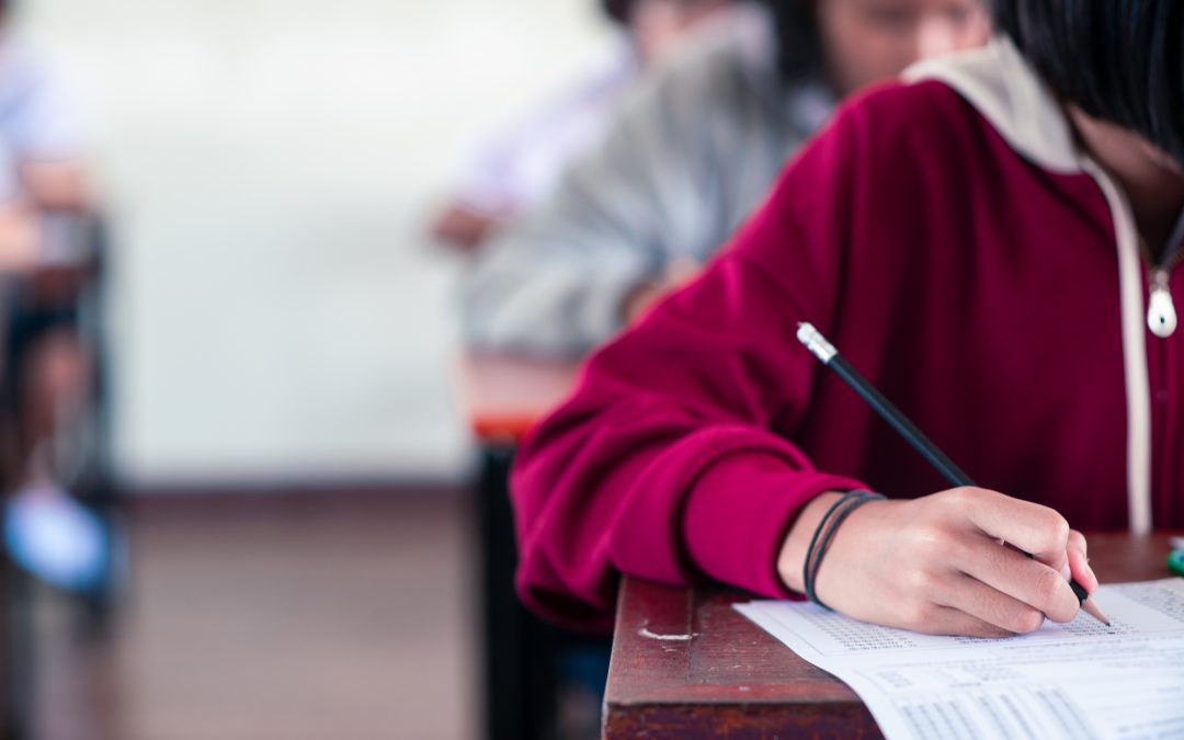 students writing and reading exam answer sheets exercises in classroom of school with stress